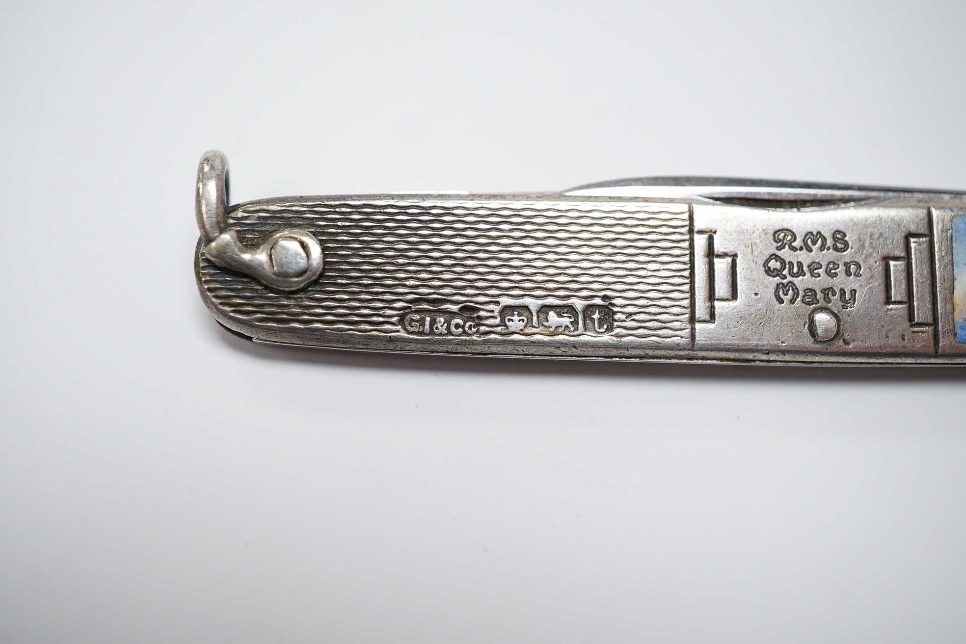 A George V engine turned silver and enamel pocket knife, decorated with R.M.S Queen Mary, the blades lifted by the handles, George Ibberson & Co, Sheffield, 1936, 76mm. Condition - poor to fair